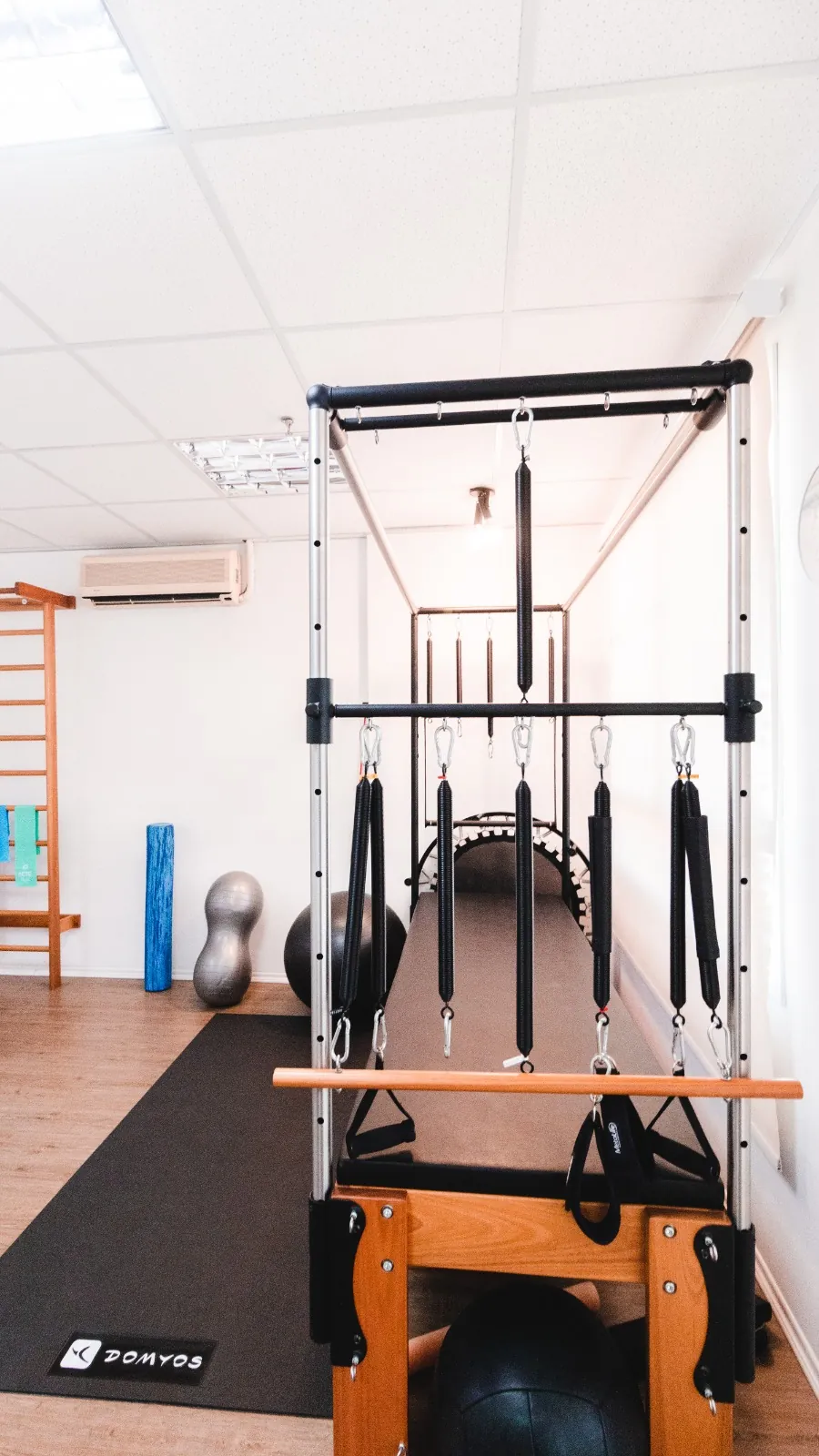 Aparelho de pilates com molas e alças sobre tapete de exercícios